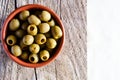 Pitted pickled green olives in a ceramic bowl on a wooden board on a light background. Healthy food concept. Royalty Free Stock Photo