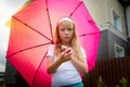 Pity blonde child with pink umbrella under the summer rain with su. Girl enjoying rainfall. Kid playing on the nature Royalty Free Stock Photo