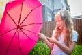 Pity blonde child with pink umbrella under the summer rain with su. Girl enjoying rainfall. Kid playing on the nature Royalty Free Stock Photo