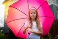 Pity blonde child with pink umbrella under the summer rain with su. Girl enjoying rainfall. Kid playing on the nature Royalty Free Stock Photo