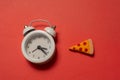 Alarm clock with a piece of pizza.  Pizza time. Snack time Royalty Free Stock Photo