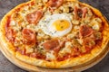 Pizza Alla Bismarck a basic pizza dough is topped with tomato sauce, mozzarella, mushrooms, prosciutto, and egg closeup on the Royalty Free Stock Photo