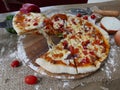 A pizza with a background of brown fabric on a tray decorated with peppers and onions