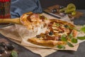 Pizza with bacon, basil, olives, pickles and mozzarella cheese close-up on parchment paper on a dark background. Delicious fresh Royalty Free Stock Photo