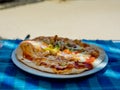 Pizza with bacon and green spicy pepper on a plate on a blue tablecloth in a cafe.