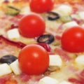 Pizza with bacon, olives, cherry tomatoes, goat cheese, green pe