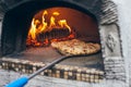 Pizza baking on the deck of a wood-fired oven. The process of making homemade pizza. The concept of homemade fast food. Royalty Free Stock Photo