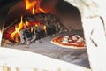 Pizza baking on the deck of a wood-fired oven. The process of making homemade pizza. The concept of homemade fast food. Royalty Free Stock Photo