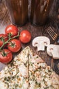 Pizza, beer, champignons and cherry tomatoes on a wooden background