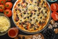 Pizza on a black background with ingredients, tomatoes, salami, mushrooms, sauce and mazzarella cheese. Italian pizza, culinary