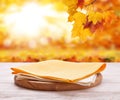 Pizza board with towel on wooden desk. Autumn background. Top view mock up. Selective focus.