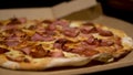 Pizza carnivor made of bacon, sausage and ham. Fast-food photography detail view of a pizza in a delivery box. Home delivered food