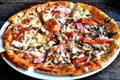 Pizza with cheese, bacon, tomato and herbs in a white bowl on a background of old boards. Royalty Free Stock Photo