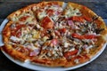 Pizza with cheese, bacon, tomato and herbs in a white bowl on a background of old boards. Royalty Free Stock Photo