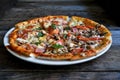 Pizza with cheese, bacon, tomato and herbs in a white bowl on a background of old boards. Royalty Free Stock Photo