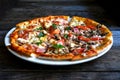 Pizza with cheese, bacon, tomato and herbs in a white bowl on a background of old boards. Royalty Free Stock Photo