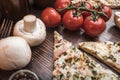 Pizza, cherry tomatoes and mushrooms on a wooden background