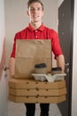 pizza and coffee delivery, a Caucasian man in a red uniform delivers pizza, handles pizza boxes, gives food to the Royalty Free Stock Photo