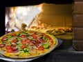 Pizza coming out of a wood burning pizza oven.