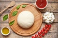 Pizza cooking ingredients on cutting board. Dough, mozzarella, tomatoes, basil, olive oil, spices. Work with the dough Royalty Free Stock Photo