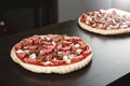 Pizza cooking, meat of chiken, sausage salami, thick dough, pizza crust, pizza is on a dark table, pizza with chicken and sausage