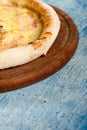 Pizza with a crispy crust on a wooden dance on a blue textured background.