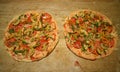 Pizza crusts topped with tomatoes and mushrooms before baking