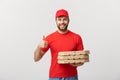 Pizza delivery concept. Young handsome delivery man showing pizza box and holding thumb up sign. Isolated on white Royalty Free Stock Photo