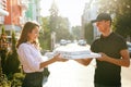 Pizza Delivery. Courier Giving Woman Boxes With Food Outdoors Royalty Free Stock Photo