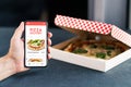 Pizza delivery and food app in phone. Online order restaurant take away. Lunch menu in cellphone screen with takeout box.