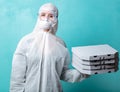 Pizza delivery girl with boxes in protective suit on blue background