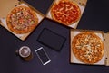 Pizza delivery. Open boxes, beer mug, tablet and smartphone with blank screen on dark background. Call or order online.