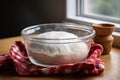pizza dough in a glass bowl covered with a kitchen towel for rising Royalty Free Stock Photo