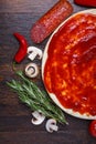 Pizza dough with sauce and different ingredients