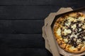 Pizza funghi in an open delivery box, dark backdrop.