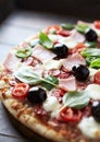 Pizza with ham, mozzarella cheese, cherry tomatoes, green and jalapeno pepper, black olives and fresh basil. Royalty Free Stock Photo