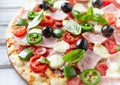 Pizza with ham, mozzarella cheese, cherry tomatoes, green and jalapeno pepper, black olives and fresh basil. Royalty Free Stock Photo