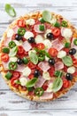 Pizza with ham, mozzarella cheese, cherry tomatoes, green and jalapeno pepper, black olives and fresh basil. Royalty Free Stock Photo