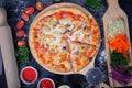 Pizza ham,mushrooms, tomatoes and cheese. on a Black table with ingredients around Royalty Free Stock Photo