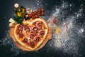 Pizza heart shaped with pepperoni, tomatoes, mozzarella, garlic and parsley Royalty Free Stock Photo