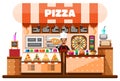 Pizza house interior with italian pizzaiolo holding hot pizza and standing behind of desks counter with pizza making
