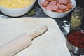 Pizza ingredients. dough with rolling pin and flour. sliced sausages. grated cheese and pizza sauce