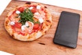 Pizza, Italian food delivery, call or order online on mobile, cellular, smart phone. Pizza and mobile phone on a wooden background Royalty Free Stock Photo