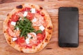 Pizza, Italian food delivery, call or order online on mobile, cellular, smart phone. Pizza and mobile phone on a wooden background Royalty Free Stock Photo