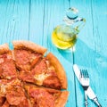 Pizza with knite and fork on blue wooden table.