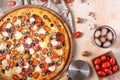 Pizza. Light background. In the right corner of the photo we see a pizza knife, tomatoes, mushrooms. Careful viewing. Focusing on