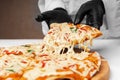 The pizza maker picks up a slice of pizza, stretches the melted cheese Royalty Free Stock Photo