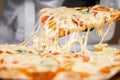 The pizza maker picks up a slice of pizza, stretches the melted cheese Royalty Free Stock Photo