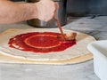 Pizza Maker puts on the sauce Royalty Free Stock Photo