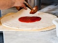 Pizza Maker puts on the sauce Royalty Free Stock Photo